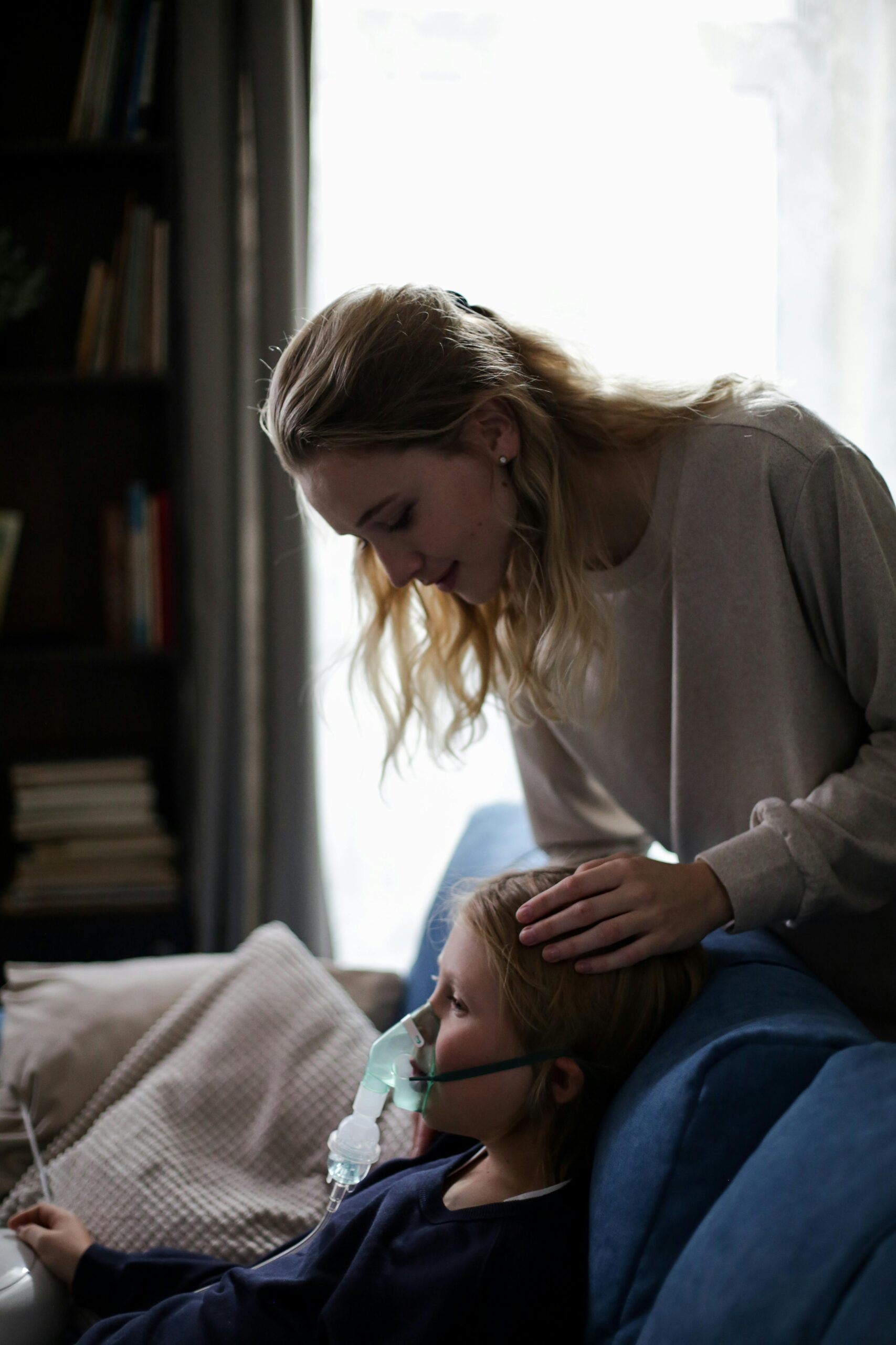 A mother tends to her sick child using an inhaler, emphasizing care and health.